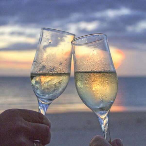 Hands holding Champagne glasses on the beach