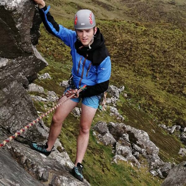 Young man rock climbing holding on to rope