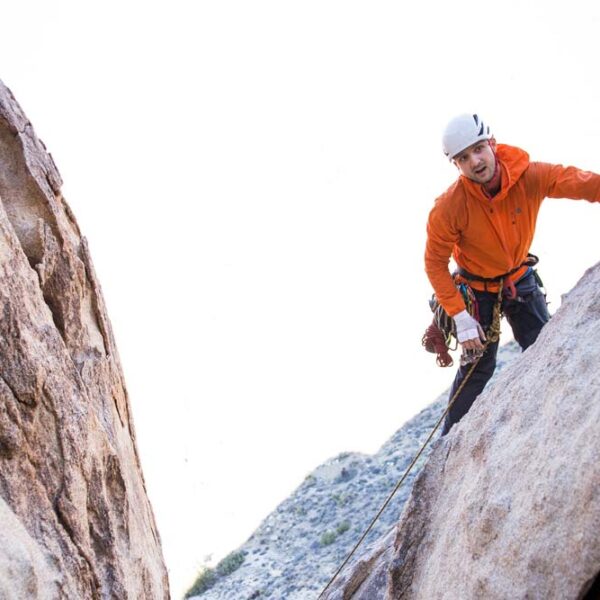 man abseiling looks around cliff edge