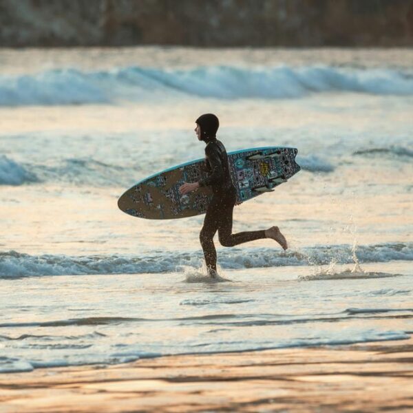 Teenage Surfer running into the water with surfboard
